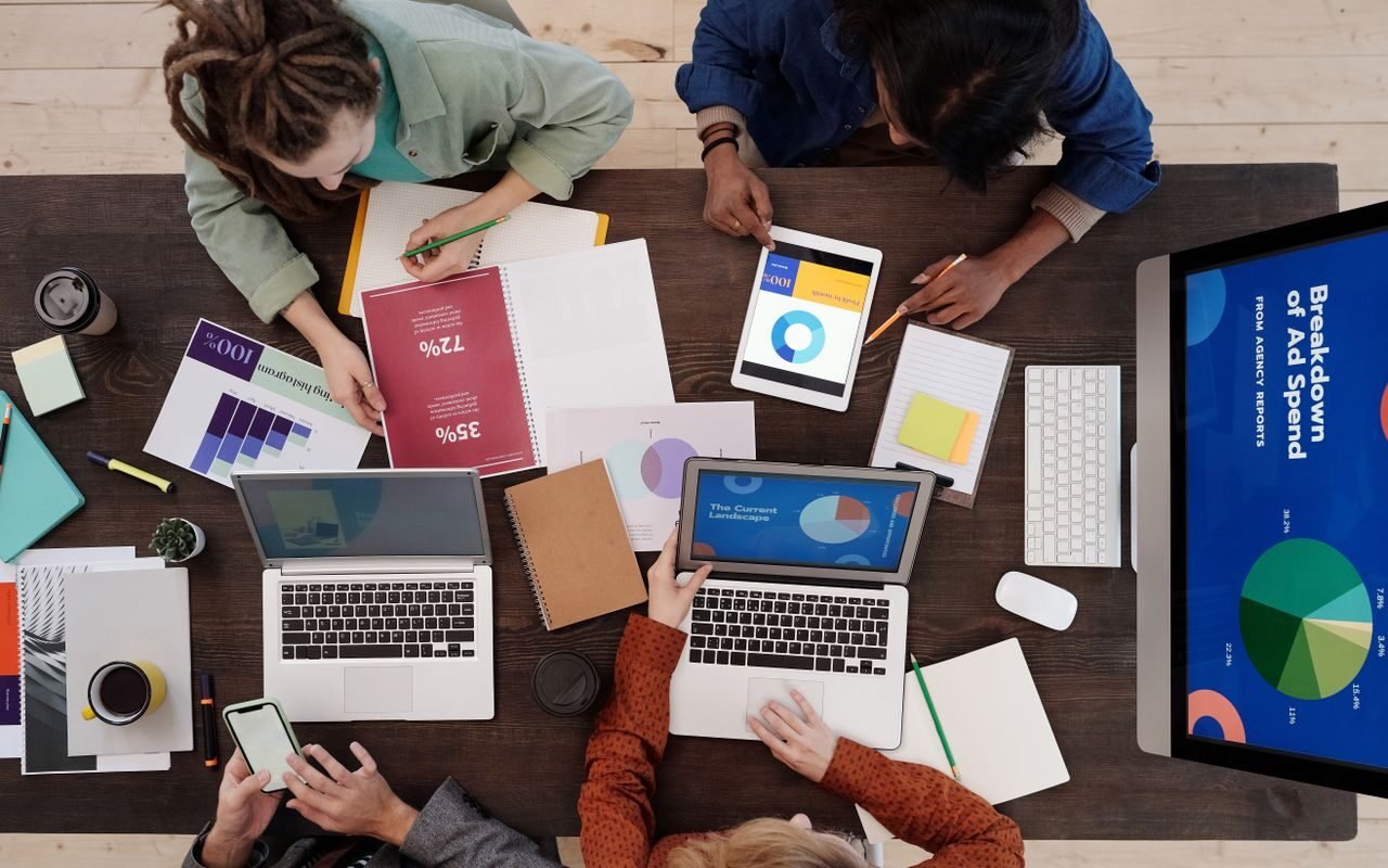A diverse team collaborating on digital marketing strategies at a desk, using laptops and tablets.
